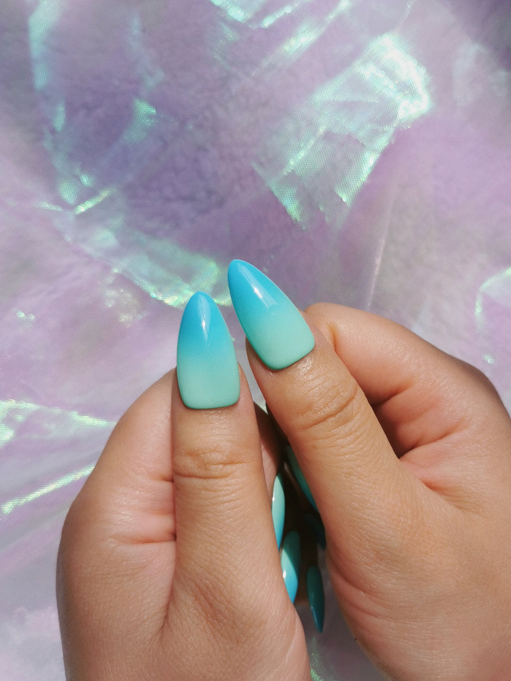 Close-up view of mint blue ombre almond press-on nail design