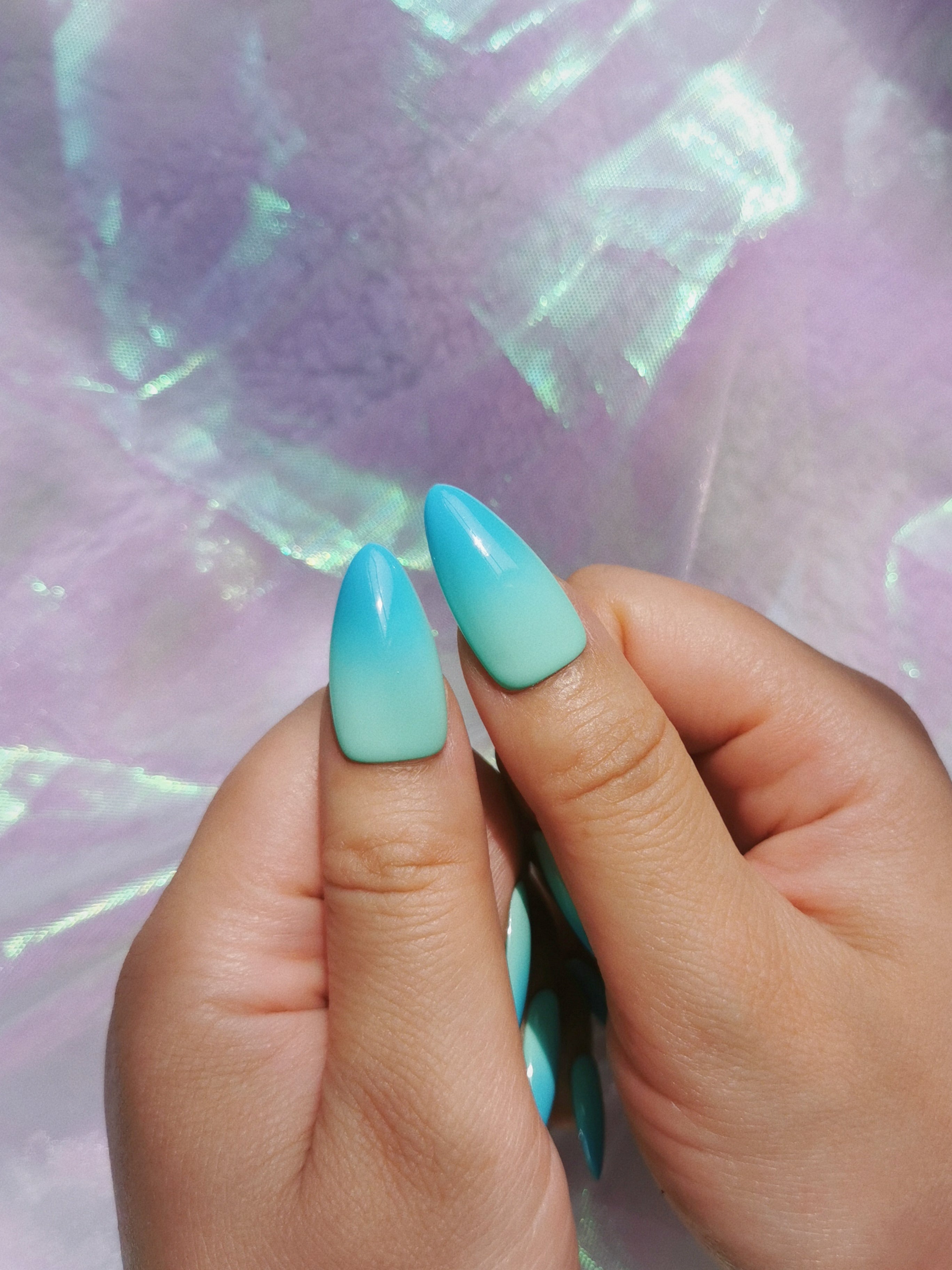 Close-up view of mint blue ombre almond press-on nail design
