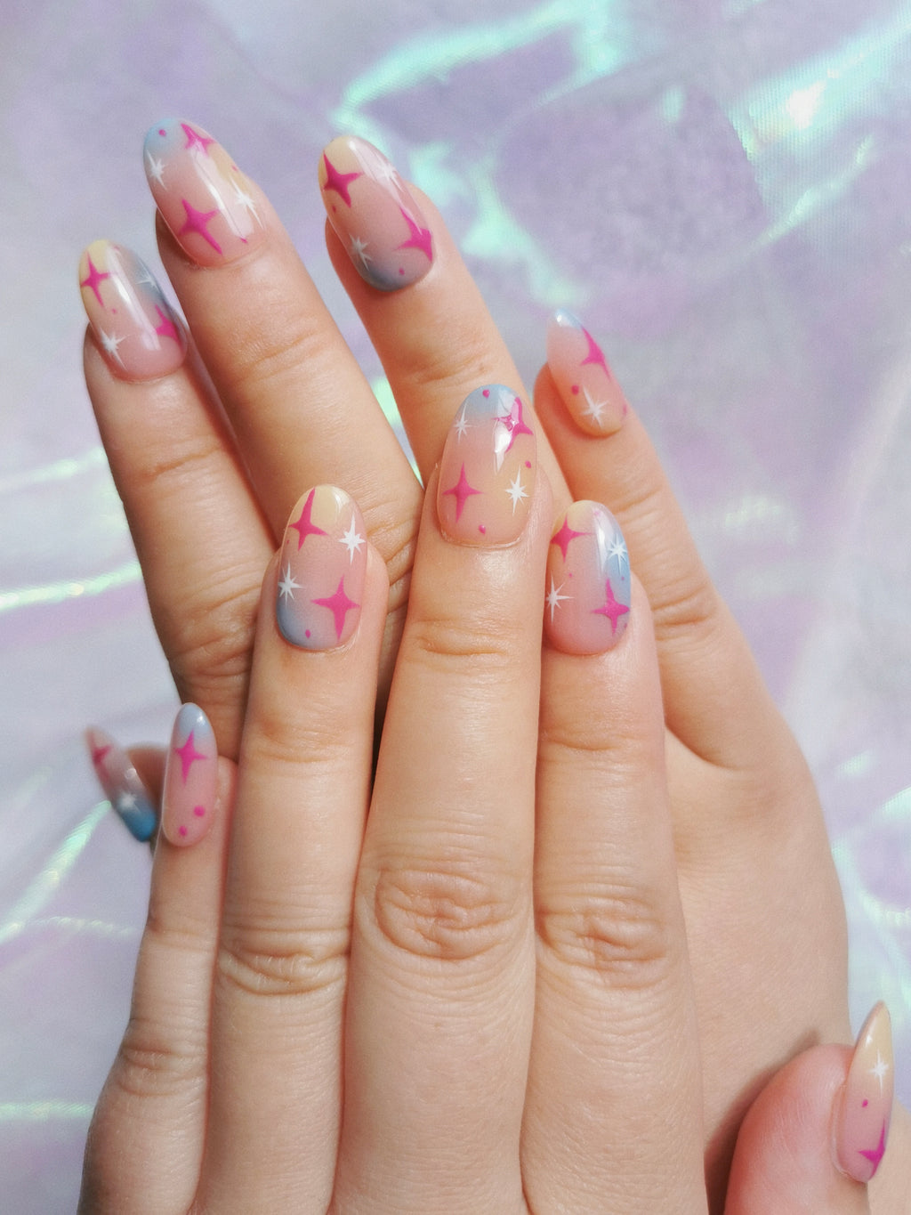 Pink blue and warm gold gradient star nails displayed on both hands