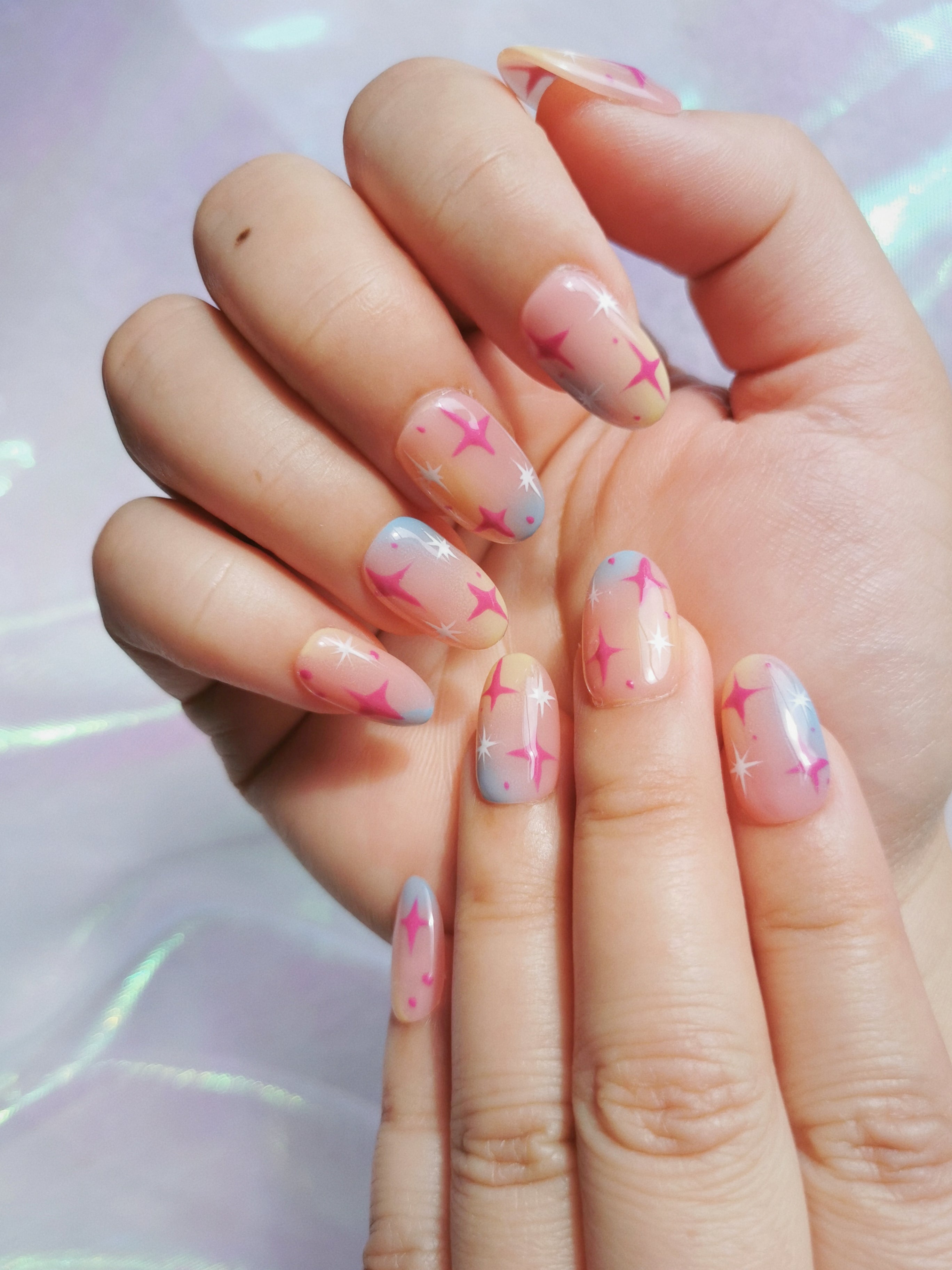 Close-up of glossy pink and blue gradient nails with magenta starbursts