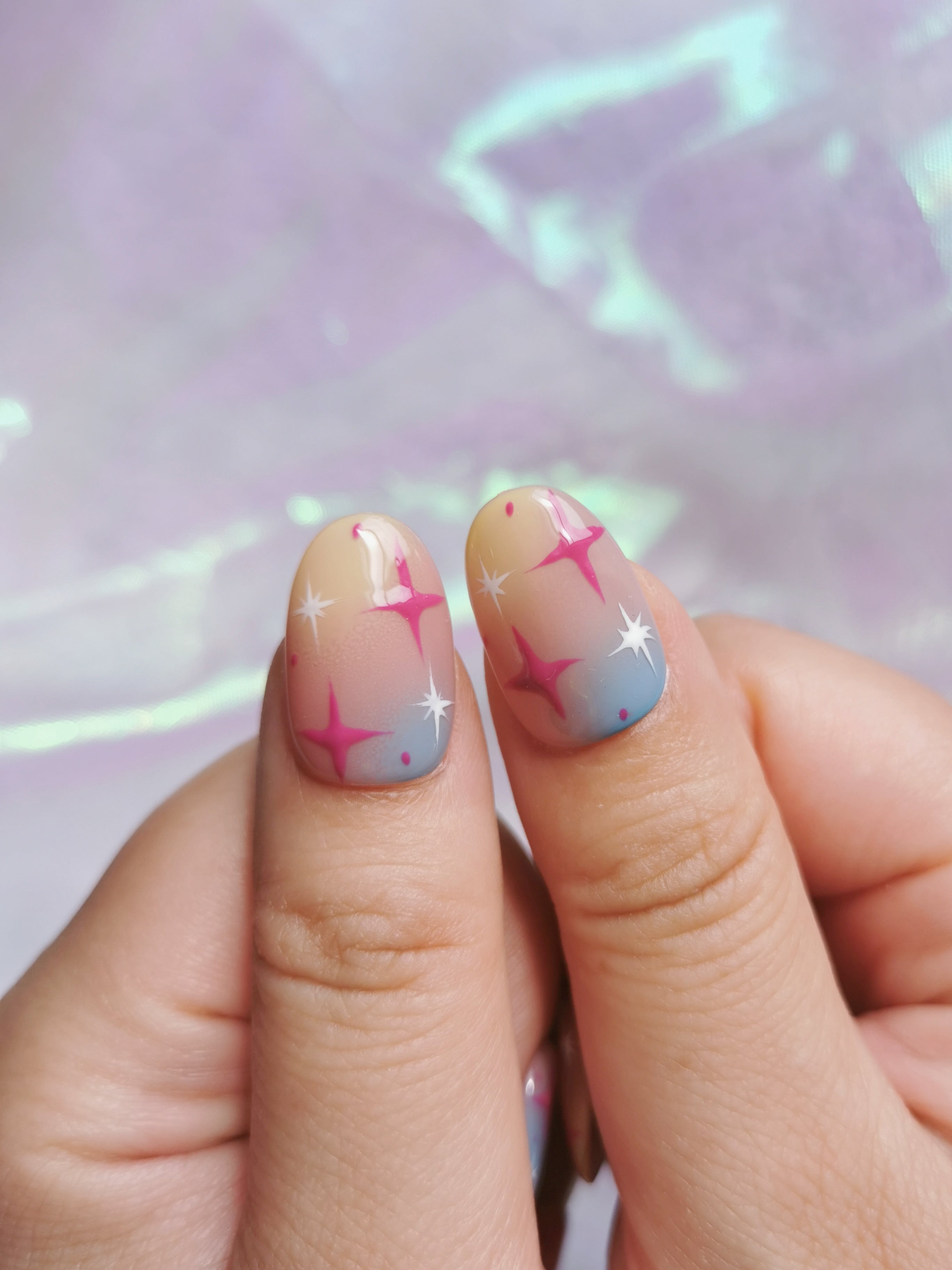 Detail view of two Y2K gradient nails with pink and white stars